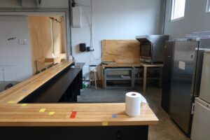 Keukenruimte aan het Gedempt Hamerkanaal met houten bar, rvs-apparatuur en een industriële uitstraling.
